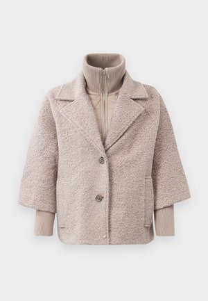 Veste surdimensionnée beige clair avec une texture duveteuse, revers en dent de chien, deux boutons et un col côtelé. Elle présente une couche intérieure matelassée.