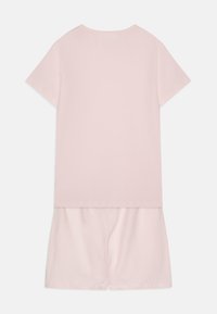 Ροζ βαμβακερή συνδυασμένη ενδυμασία που περιλαμβάνει ένα κοντομάνικο τοπ με φαρδιά γραμμή και αντίστοιχες σορτς, και οι δύο με απαλή, λεία υφή.