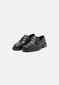 Mocasines de cuero negro con punta redonda, que presentan dos bandas horizontales en la parte superior. Textura lisa con un tacón bajo y plano.