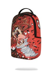 Mochila roja con un gráfico de un personaje de dibujos animados con la boca abierta, patrón de cuadros negro y diseño de espiral blanca en la base.