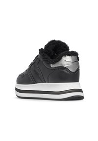 Sneaker nera con suola bianca, dettaglio in argento sul tallone e rivestimento interno nero e morbido, mostrata da un angolo posteriore su uno sfondo bianco.