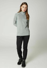 Lys grå, langærmet pullover med kvart lynlås og kontrastfarvede teal detaljer, parret med sorte, tætsiddende bukser og sorte vandrestøvler.