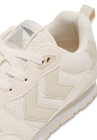 Lys kremfargede sneakers laget av netting og semsket skinn, med et chevron-design, flate snører og en polstret krage for komfort.
