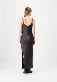 Ilgas, tamsiai pilkas suknelė su išpjova nugaroje, prigludusi ir su šonine plyšio. Lygus audinys ir minimalistinis dizainas išryškina elegantišką išvaizdą.