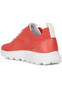 Baskets en tricot corail avec une semelle en caoutchouc blanc. Comprend un dessus texturé, un poignet élastiqué et des lacets décoratifs sur le côté.