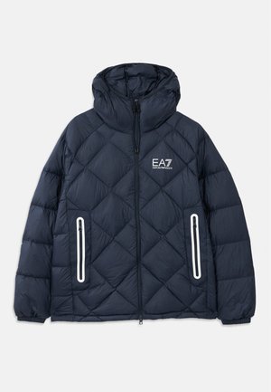 Giubbotto imbottito trapuntato blu navy con cappuccio, zip frontale, due tasche verticali con zip e bordo bianco, e logo EA7 Emporio Armani sul petto.