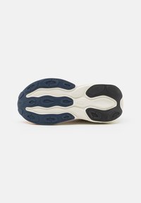 Suela de una zapatilla con una desgastada de goma segmentada en navy, negro y blanco para tracción sobre un fondo blanco liso.