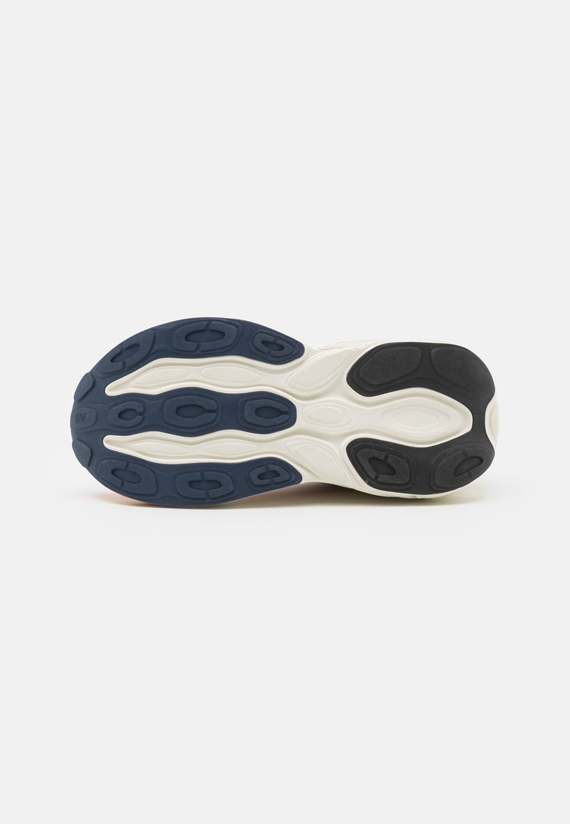 Suela de una zapatilla con una desgastada de goma segmentada en navy, negro y blanco para tracción sobre un fondo blanco liso.