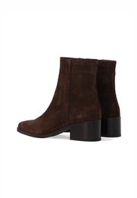 Brązowe zamszowe botki na kostkę z zaokrąglonym noskiem i słupkowym obcasem. Gładka faktura, średniej wysokości cholewka oraz minimalne przeszycia.