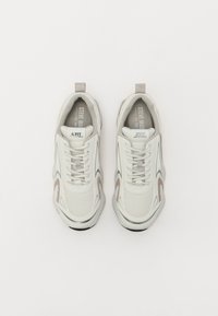 Hvide mesh sneakers med grå detaljer, rund tå, snørebånd og en trækflap. Logo synligt på tungen. Struktureret gummisål.