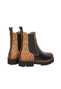 Schwarze Chelsea-Stiefel mit einem gepunkteten, tanfarbenen Einsatz, kontrastierenden schwarzen elastischen Seiten und einer strukturierten Sohle mit roten Nähdetails.