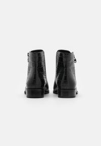 Bottines en cuir noir avec une texture crocodile brillante et un petit talon carré, dotées d'une fermeture éclair et d'un bout arrondi.