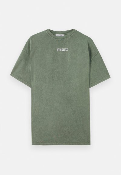 T-shirt de algodão verde com gola redonda, mangas curtas e um logo impresso "STIEGLITZ" no peito. Textura suave e corte descontraído.