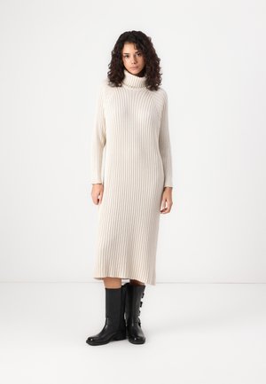 Cream ribbed turtleneck dress, mid-length with long sleeves, paired with black knee-high boots featuring side buttons.