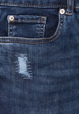 Tejido de mezclilla azul oscuro que presenta un área pequeña desgastada con hilos blancos visibles y un bolsillo para monedas asegurado por un botón de metal.