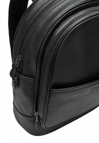 Czarny skórzany plecak z dwoma zasuwanymi przegrodami, teksturowane wykończenie, zaokrąglony kształt i gładka podstawa; posiada subtelny detal z logo.