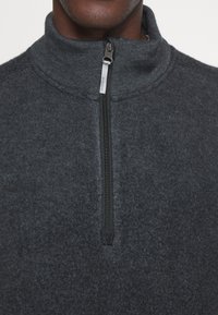 Dunkelgrauer Fleecepullover mit hohem Kragen und einem Viertel-Rei�ßverschluss, weicher Textur und minimalen Nähedetails.
