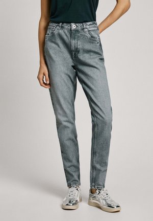 Light blue straight-leg jeans with a high waist, five pockets, and subtle whiskering; paired with reflective sneakers.
