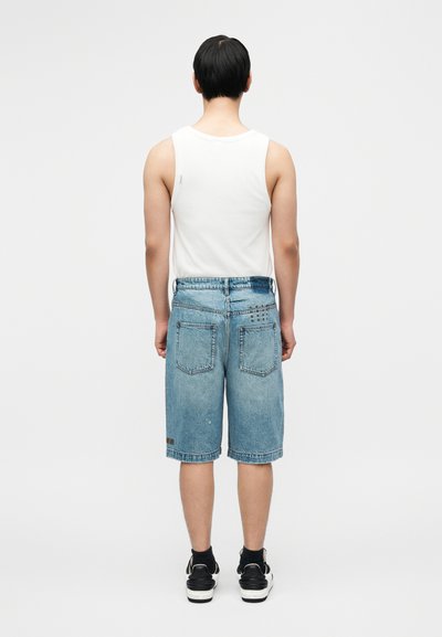 Τζιν σορτς σε ανοιχτό μπλε χρώμα με άνετη εφαρμογή, διαθέτουν δύο πίσω τσέπες, τονικό ράψιμο και δερμάτινο λογότυπο της μάρκας. Φορεμένα με λευκό τοπ μπλουζάκι.