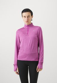 Majica s dugim rukavima i visokim ovratnikom izrađena od heathered ružičaste tkanine. Ima zatvarač i rupice za palčeve. Nike logo prisutan na grudima.
