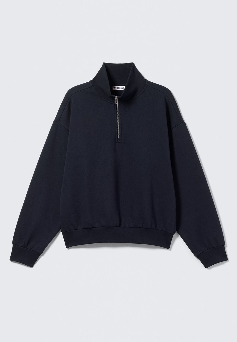 Sweatshirt noir à manches longues avec un col montant et une fermeture éclair partielle à l'avant, poignets et ourlet côtelés, étiquette "WEEKDAY" à l'intérieur du col.