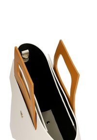 Biała skórzana torba z brązowymi uchwytami, z otwartą górą i czarnym wnętrzem. Zawiera zapięcie na zatrzask oraz ozdobny akcent z boku.