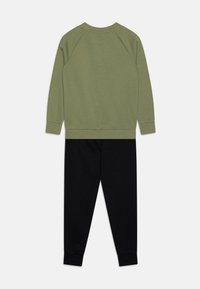 Sudadera verde oliva con mangas largas y pantalones deportivos negros. Ambos tienen puños acanalados y una tela suave y texturizada.