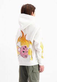 Witte hoodie met een kleurrafische afbeelding op de achterkant van een roze gezicht en oranje vlammen. Lange mouwen met ontwerpelementen.