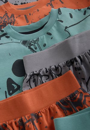 Quatre vêtements superposés : un haut vert menthe avec des motifs noirs, un haut orange, un bas gris avec taille côtelée, et un bas orange à motifs.