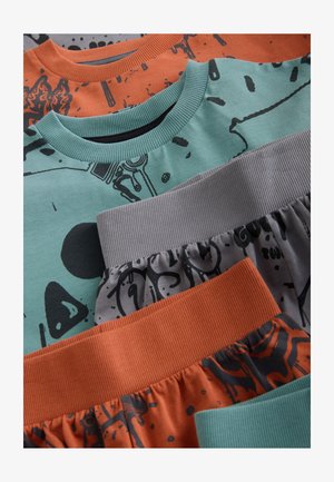 Négy ruhadarab fed egymáson: egy mentazöld felső fekete grafikával, egy narancssárga felső, egy szürke alsó bordázott derékrésszel, és egy mintás narancssárga alsó.