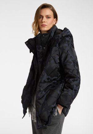 Chaqueta acolchada negra con capucha oversize, que presenta un patrón abstracto tonal, botones a presión y bolsillos laterales. Tejido liso e insulated.