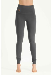 Grijze leggings met een hoge tailleband, gemaakt van zachte, rekbare stof, met een geborduurd oranje logo aan de linkervoorzijde.