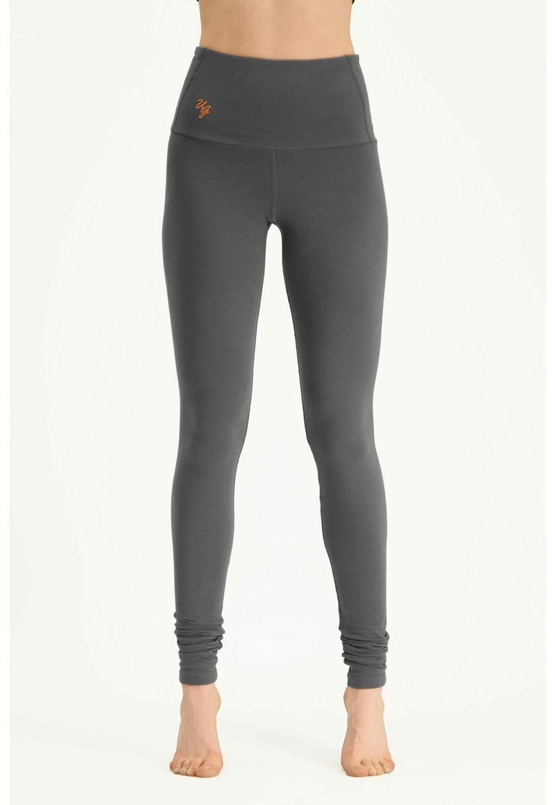 Grijze leggings met een hoge tailleband, gemaakt van zachte, rekbare stof, met een geborduurd oranje logo aan de linkervoorzijde.