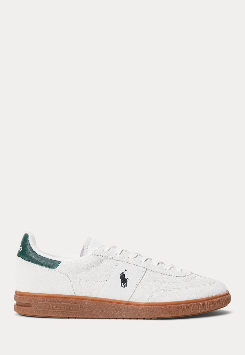 Witte suède lage sneaker met een bruine rubberen zool, groene hakaccent, zwart Polo Ralph Lauren-logo aan de zijkant en witte veters.