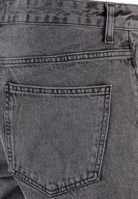 Pelēki denim bikses ir ar aizmugures kabatu, kurai ir kontrastējoša izšūšana, tām ir gluda tekstūra un pieguļošs dizains.