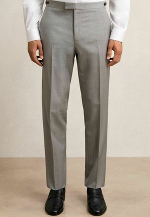 Graue maßgeschneiderte Hose mit glatter Textur, scharfen Falten, flachem Frontbereich und subtiler Schattierung, kombiniert mit schwarzen Slippern.