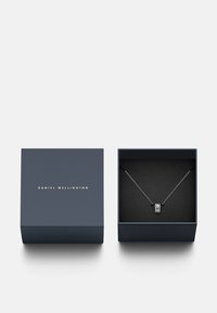 Meriinikauhan sininen korulaukkukulta teksti "DANIEL WELLINGTON", sisältäen hopeaketjun, jossa on pyöreä riipus, jossa on tekstuuripintaa.