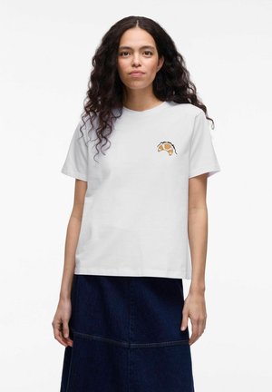 T-shirt en coton blanc avec un graphique de croissant en marron et contour noir sur la poitrine gauche, associé à une jupe en denim foncé.