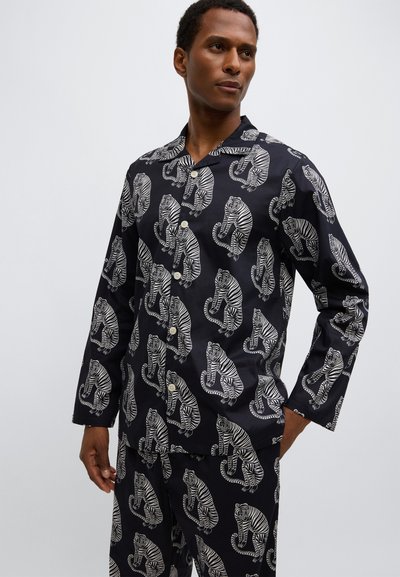 Completo pigiama nero con motivo a tigre bianca. Comprende una camicia a maniche lunghe con bottoni e pantaloni larghi realizzati in tessuto liscio.