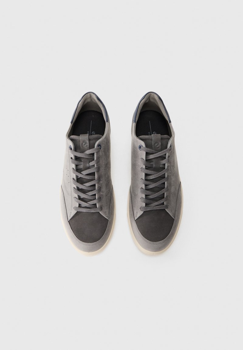 Szare zamszowe sneakersy z ciemnoszarym noskiem, płaskimi sznurowadłami i beżową gumową podeszwą. Wnętrze ma ciemną wkładkę.