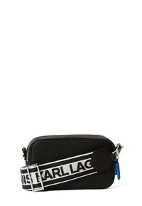 Schwarze Leder-Crossbody-Tasche mit einem Reißverschluss, ausgestattet mit einem weißen Markenriemen und einem blauen Akzent, der vom Reißverschluss hängt.