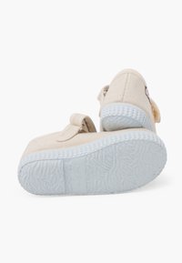 Scarpe in tela beige con strap in Velcro, suole in gomma e suole esterne texturizzate di un leggero blu. Design semplice con un piccolo dettaglio del logo.