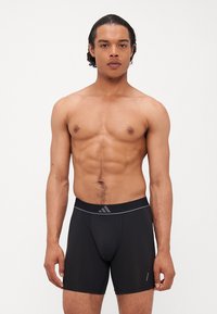Bermudas atléticas pretas com um design justo, feitas de um tecido elástico. Apresentam uma cintura larga com uma marcação cinza e sem padrões visíveis.