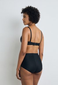 Set de lenjerie neagră, care include un sutien moale cu bretele ajustabile și chiloți cu talie înaltă. Materialul pare neted, având un design clasic.