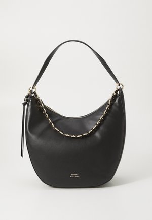 Μαύρη δερμάτινη τσάντα χειρός με καμπυλωτό σχήμα, μεταλλική αλυσίδα στη λαβή και κλείσιμο με φερμουάρ. Χρυσά εξαρτήματα και λογότυπο στην μπροστινή πλευρά.