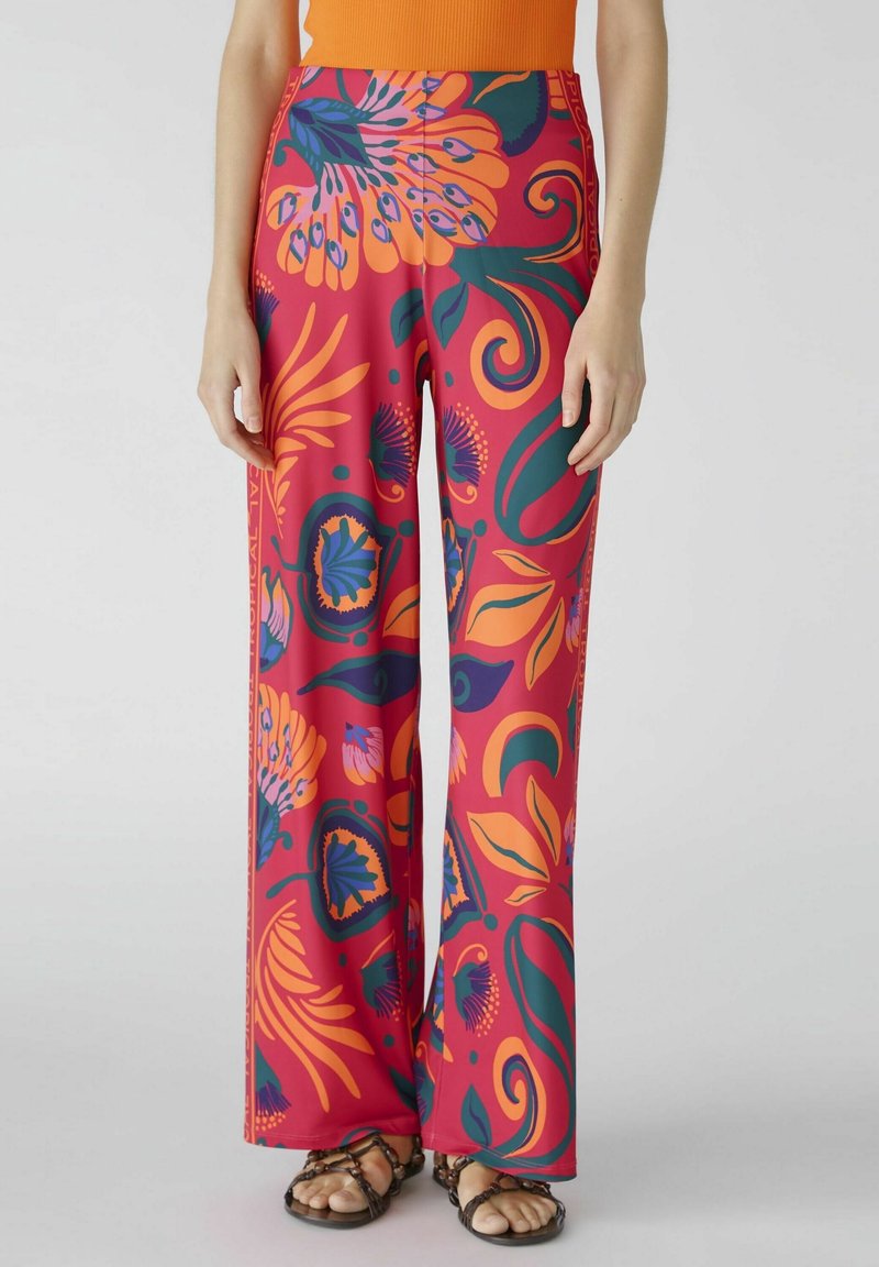 Pantalons larges avec un motif floral audacieux en rose, orange et vert. Fabriqués dans un matériau lisse et léger avec une taille haute.