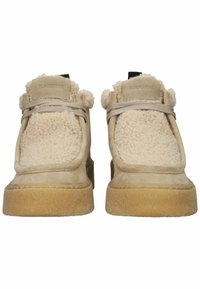 Chaussures en daim beige avec une doublure douce et texturée et une semelle en caoutchouc plate, couleur tan. Design à lacets avec un bout rond et des accents doux en haut.