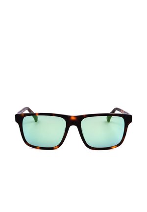 Occhiali da sole rettangolari tartarugati con lenti riflettenti verde chiaro appoggiati su uno sfondo bianco.