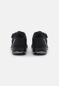 Black athletic shoes with a mesh upper, toggle lacing, and durable rubber soles featuring a camouflage pattern.