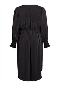 Vestido midi negro con mangas largas abullonadas, cinturilla elástica y puños fruncidos, visto desde atrás sobre un fondo blanco.